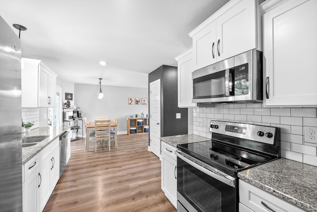 1341 Sussex Dr, Clarksville, TN 37042 - kitchen featuring stainless steel appliances, white cabinetry, decorative backsplash, light wood-style floors, and light stone countertops
