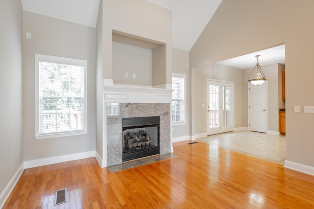 4370 Wellesley Dr, Ooltewah, TN 37363 - unfurnished living room featuring light wood-style flooring, a tiled fireplace, baseboards, and high vaulted ceiling