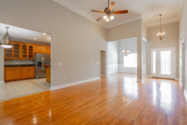 4370 Wellesley Dr, Ooltewah, TN 37363 - unfurnished living room featuring a chandelier, a high ceiling, crown molding, light wood-style flooring, and a ceiling fan