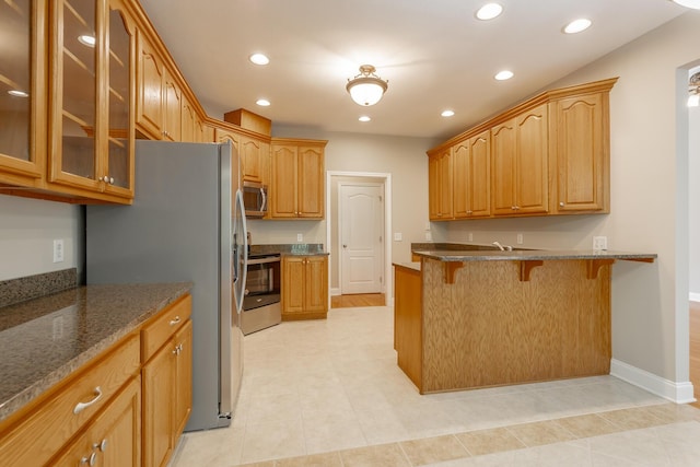 4370 Wellesley Dr, Ooltewah, TN 37363 - kitchen with appliances with stainless steel finishes, a breakfast bar, glass insert cabinets, a peninsula, and dark stone countertops