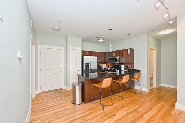 817 3rd Ave N Unit 411, Nashville, TN 37201 - kitchen featuring appliances with stainless steel finishes, a peninsula, backsplash, light wood-type flooring, and dark countertops