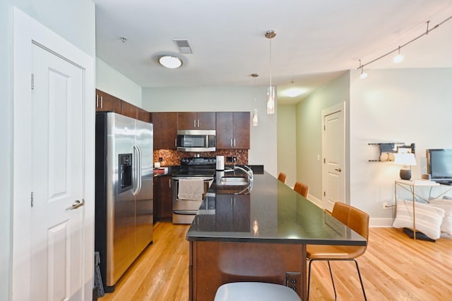 817 3rd Ave N Unit 411, Nashville, TN 37201 - kitchen featuring stainless steel appliances, dark countertops, light wood-style floors, an island with sink, and decorative backsplash