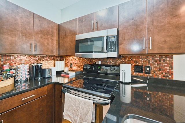 817 3rd Ave N Unit 411, Nashville, TN 37201 - kitchen featuring appliances with stainless steel finishes, decorative backsplash, dark brown cabinetry, and dark stone countertops