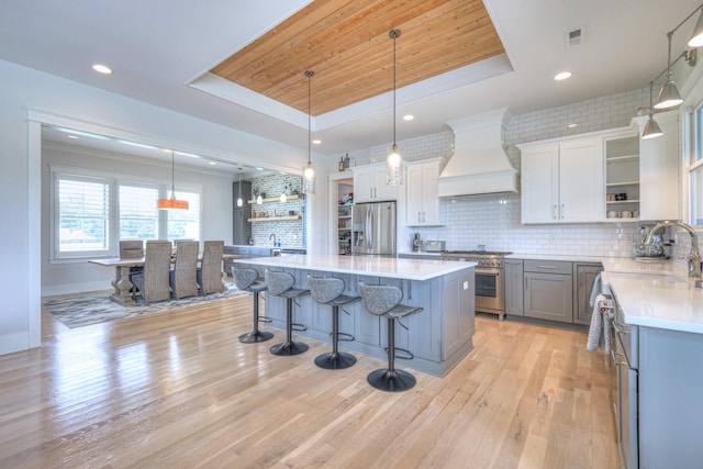 2117 Southern Preserve Ln, Franklin, TN 37064 - kitchen featuring stainless steel appliances, open shelves, a tray ceiling, custom exhaust hood, and a breakfast bar area