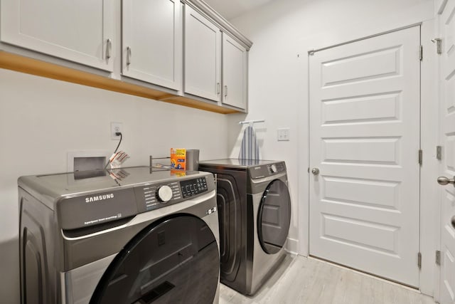3650 Riggins Rd, Cumberland Furnace, TN 37051 - laundry area featuring cabinet space, washer and clothes dryer, and light wood-style floors