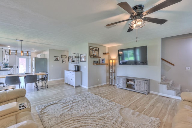 1713 Hollow Oak Dr, Lebanon, TN 37087 - living room featuring light wood-style flooring, ceiling fan, baseboards, and stairs