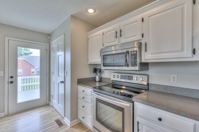 1713 Hollow Oak Dr, Lebanon, TN 37087 - kitchen with stainless steel appliances, white cabinetry, light wood-style floors, dark countertops, and recessed lighting