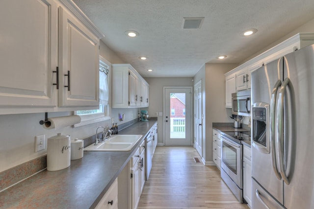 1713 Hollow Oak Dr, Lebanon, TN 37087 - kitchen with stainless steel appliances, a sink, dark countertops, a textured ceiling, and recessed lighting