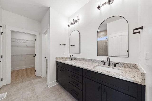 338 Dugout Rd, Summertown, TN 38483 - bathroom with double vanity, a tile shower, a spacious closet, and baseboards