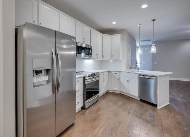 135 Grandstand Blvd, Gallatin, TN 37066 - kitchen with stainless steel appliances, a peninsula, white cabinetry, dark wood-style floors, and light countertops