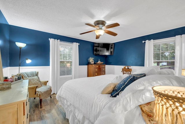 130 Shane Lee Cir, Dover, TN 37058 - bedroom with multiple windows, wood finished floors, wainscoting, ceiling fan, and a textured ceiling