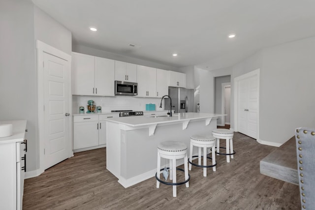 129 Southwind Run, Spring Hill, TN 37174 - kitchen featuring appliances with stainless steel finishes, tasteful backsplash, dark wood-style floors, a kitchen island with sink, and white cabinets