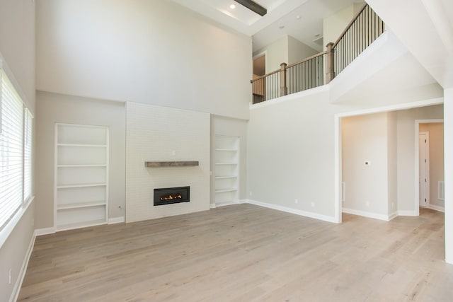 5956 Hunt Valley Dr, Spring Hill, TN 37174 - unfurnished living room featuring a towering ceiling, built in features, plenty of natural light, wood finished floors, and a fireplace