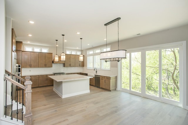 5956 Hunt Valley Dr, Spring Hill, TN 37174 - kitchen featuring dishwasher, light countertops, a kitchen island, light wood finished floors, and brown cabinets