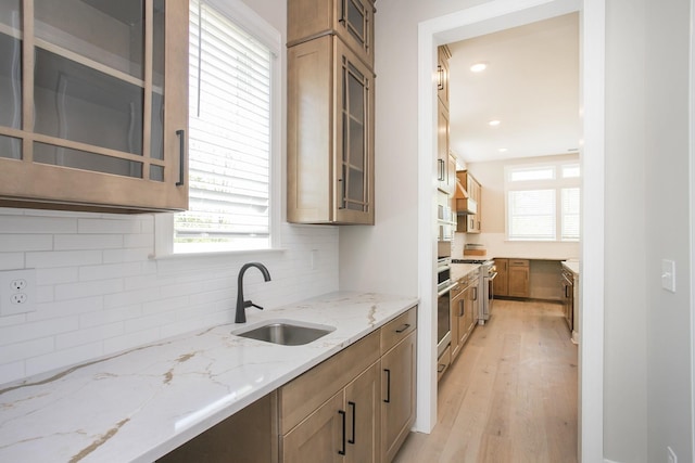 5956 Hunt Valley Dr, Spring Hill, TN 37174 - kitchen featuring a sink, light wood-type flooring, decorative backsplash, light stone counters, and glass insert cabinets