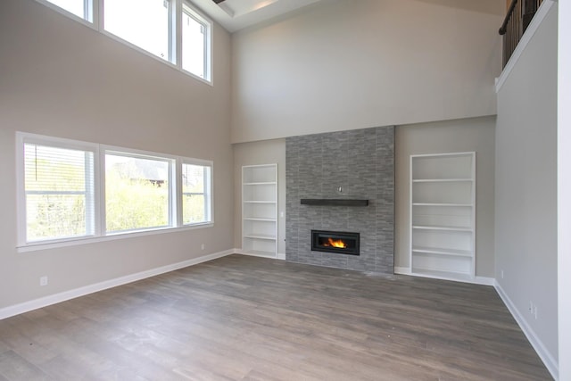 5952 Hunt Valley Dr, Spring Hill, TN 37174 - unfurnished living room featuring built in features, a towering ceiling, baseboards, plenty of natural light, and wood finished floors