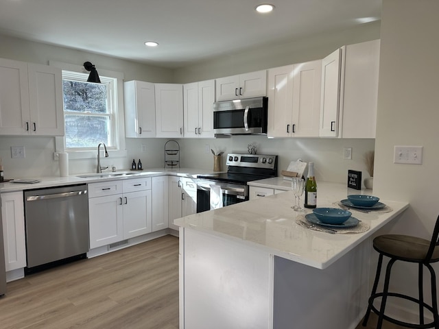 1320 Napier Lake Rd, Hohenwald, TN 38462 - kitchen with appliances with stainless steel finishes, a sink, a peninsula, white cabinets, and a kitchen bar