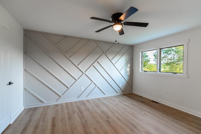 1320 Napier Lake Rd, Hohenwald, TN 38462 - unfurnished bedroom featuring light wood-style flooring, baseboards, ceiling fan, and a decorative wall