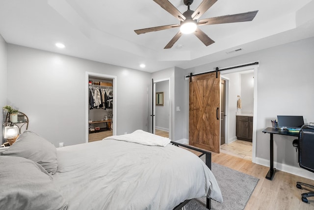 1415 Southside Rd, Southside, TN 37171 - bedroom with a barn door, a raised ceiling, a spacious closet, light wood-style flooring, and recessed lighting