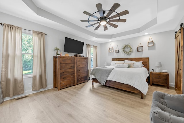 1415 Southside Rd, Southside, TN 37171 - bedroom featuring a barn door, a tray ceiling, light wood-type flooring, multiple windows, and recessed lighting