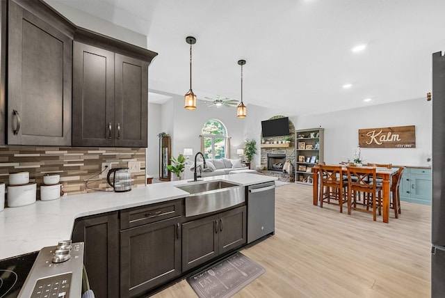 1415 Southside Rd, Southside, TN 37171 - kitchen featuring stainless steel dishwasher, a stone fireplace, a ceiling fan, decorative backsplash, and dark brown cabinetry