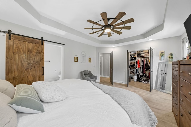 1415 Southside Rd, Southside, TN 37171 - bedroom with a raised ceiling, a barn door, light wood finished floors, a spacious closet, and ensuite bath