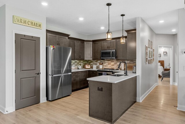 1415 Southside Rd, Southside, TN 37171 - kitchen with stainless steel appliances, dark brown cabinetry, a peninsula, tasteful backsplash, and light wood-type flooring