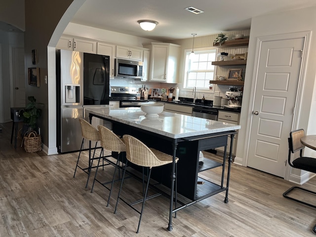 219 Dugger Dr, Clarksville, TN 37042 - kitchen featuring stainless steel appliances, open shelves, arched walkways, and light wood finished floors