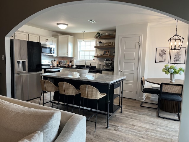 219 Dugger Dr, Clarksville, TN 37042 - kitchen with appliances with stainless steel finishes, arched walkways, white cabinets, light wood-style floors, and open shelves