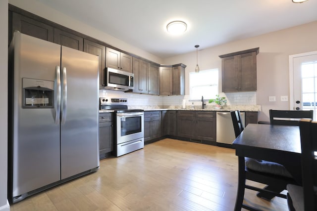 110 Saw Mill Rd, Dickson, TN 37055 - kitchen with stainless steel appliances, decorative backsplash, light stone countertops, hanging light fixtures, and light wood-style floors