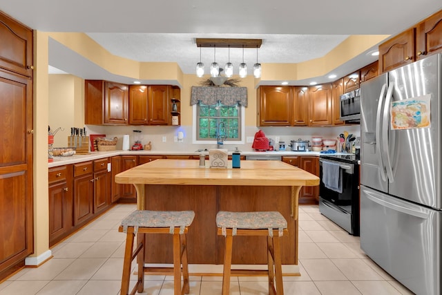 891 Deepwoods Rd, Sewanee, TN 37375 - kitchen featuring appliances with stainless steel finishes, butcher block countertops, a kitchen bar, light tile patterned flooring, and a kitchen island
