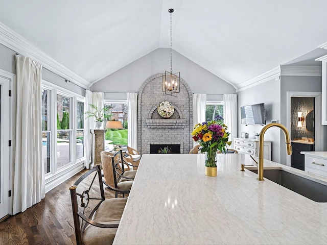 1004 Jones Pkwy, Brentwood, TN 37027 - dining room with vaulted ceiling, a brick fireplace, dark wood-style flooring, crown molding, and a chandelier