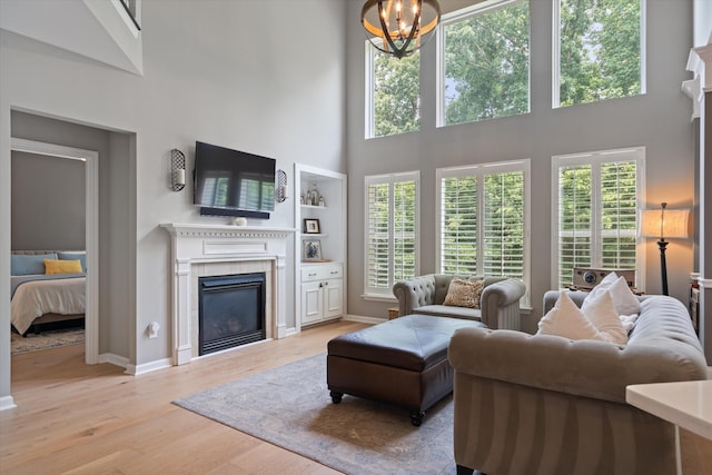 736 Arbor Springs Dr, Mount Juliet, TN 37122 - living room with a tiled fireplace, a towering ceiling, light wood-type flooring, baseboards, and a chandelier
