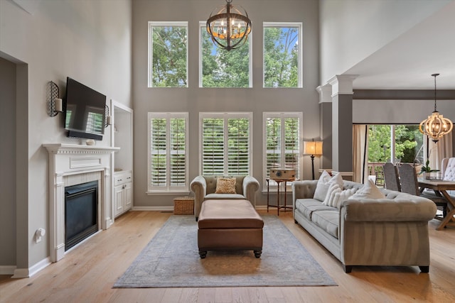 736 Arbor Springs Dr, Mount Juliet, TN 37122 - living room featuring a chandelier, a high ceiling, a glass covered fireplace, healthy amount of natural light, and light wood-style flooring