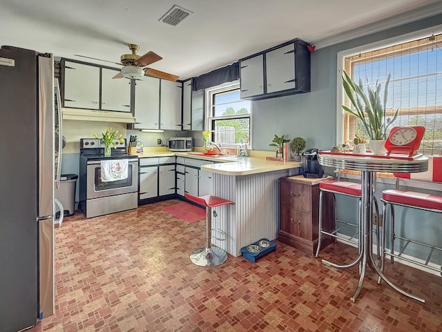 3113 Stafford Dr, Nashville, TN 37214 - kitchen with appliances with stainless steel finishes, under cabinet range hood, a ceiling fan, a peninsula, and brick patterned floors