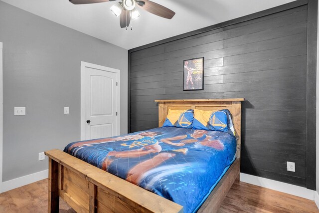 1270 Post Oak Rd, Belvidere, TN 37306 - bedroom featuring baseboards, wood finished floors, an accent wall, a ceiling fan, and wooden walls