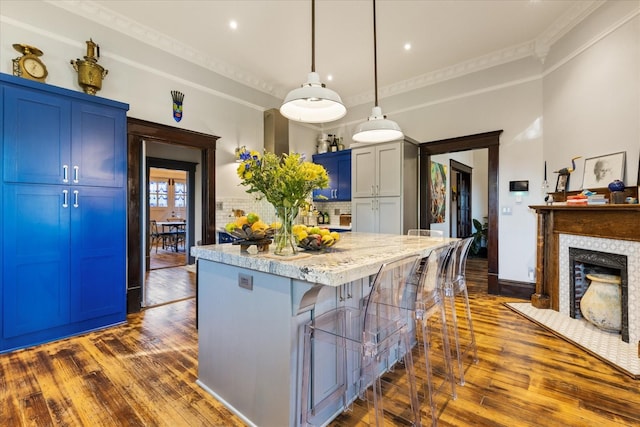 207 Main St E, Wartrace, TN 37183 - kitchen with dark wood-type flooring, ornamental molding, a kitchen bar, a center island, and tasteful backsplash