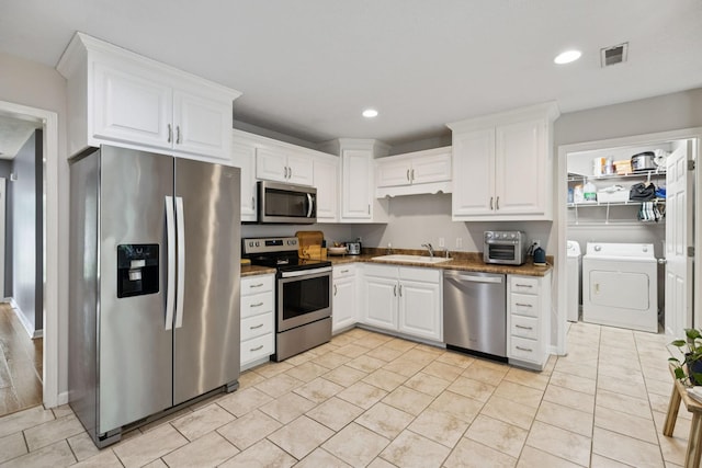 123 Hubbard St, Hohenwald, TN 38462 - kitchen featuring appliances with stainless steel finishes, washing machine and dryer, a sink, white cabinetry, and recessed lighting
