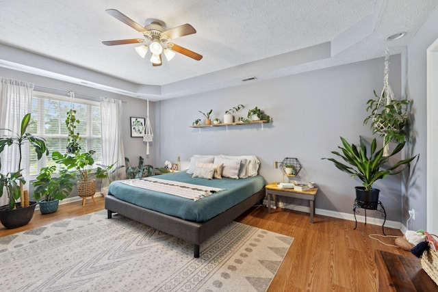 123 Hubbard St, Hohenwald, TN 38462 - bedroom with a raised ceiling, a textured ceiling, baseboards, wood finished floors, and ceiling fan