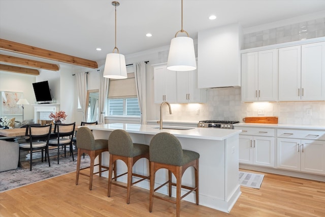 2123 Scott Ave Unit A, Nashville, TN 37216 - kitchen featuring wall chimney range hood, a sink, light wood-style floors, decorative backsplash, and a kitchen island with sink