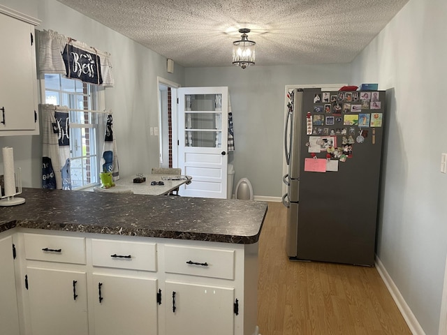 1700 Ellington Dr, Lafayette, TN 37083 - kitchen featuring freestanding refrigerator, light wood-style flooring, white cabinetry, a peninsula, and a textured ceiling