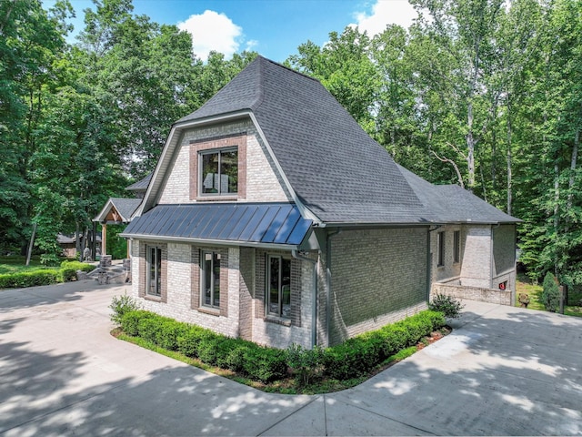 1288 Rogues Fork Rd, Bethpage, TN 37022 - view of home's exterior with brick siding, a standing seam roof, driveway, roof with shingles, and a metal roof
