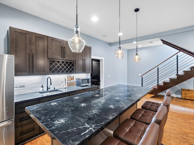 1288 Rogues Fork Rd, Bethpage, TN 37022 - kitchen featuring appliances with stainless steel finishes, backsplash, dark brown cabinets, a kitchen bar, and light wood-style floors