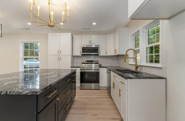 1767C W Main St, Franklin, TN 37064 - kitchen featuring stainless steel appliances, a sink, white cabinets, decorative backsplash, and dark stone counters