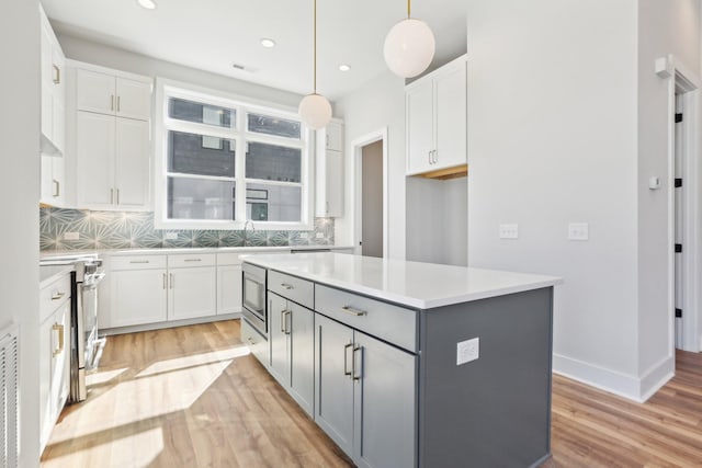 107 E 9th St Unit C6, Columbia, TN 38401 - kitchen featuring gray cabinetry, light wood-type flooring, appliances with stainless steel finishes, a kitchen island, and white cabinetry