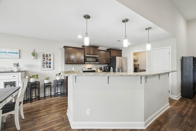 1175 Eagles Nest Ln, Clarksville, TN 37040 - kitchen featuring appliances with stainless steel finishes, dark brown cabinets, a kitchen breakfast bar, dark wood-style floors, and baseboards