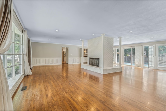 818 N Rutherford Blvd, Murfreesboro, TN 37130 - unfurnished living room featuring wood finished floors, a decorative wall, a brick fireplace, wainscoting, and ornamental molding