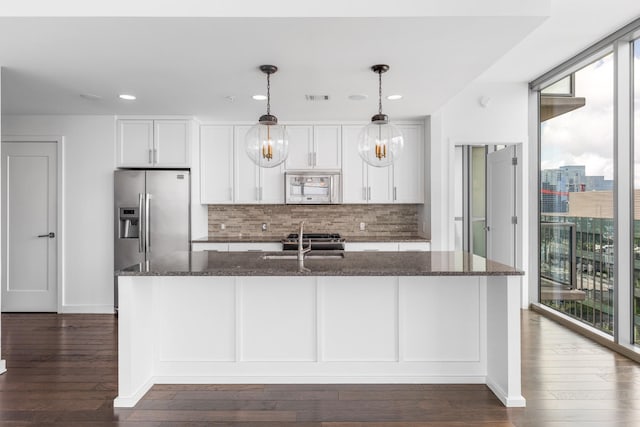 1212 Laurel St Unit 1902, Nashville, TN 37203 - kitchen featuring appliances with stainless steel finishes, tasteful backsplash, dark wood-type flooring, dark stone countertops, and white cabinets