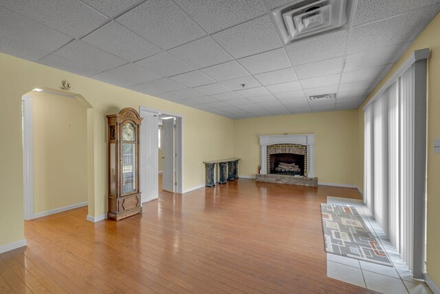 135 Carter Rd, Winchester, TN 37398 - unfurnished living room with a paneled ceiling, light wood-style floors, a fireplace, arched walkways, and baseboards