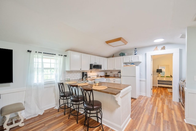 91 Creekside View Ln, Decaturville, TN 38329 - kitchen featuring white appliances, washing machine and clothes dryer, a peninsula, white cabinets, and a kitchen breakfast bar